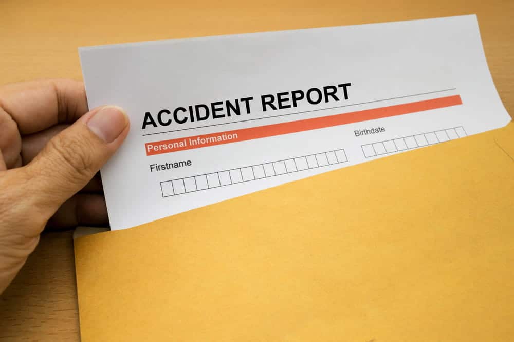 Image is of a person holding an accident report document after a roadway incident, concept of documenting injuries and evidence after biking in Aiken.