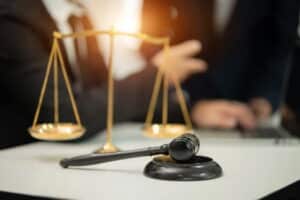 Image is of a judge’s gavel and balance scale on a desk, representing legal review of communication evidence in DV cases in Aiken