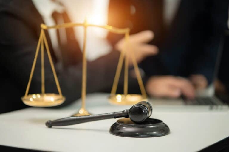 Image is of a judge’s gavel and balance scale on a desk, representing legal review of communication evidence in DV cases in Aiken