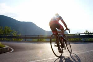 Image is of a cyclist riding outdoors on a winding road, illustrating real world scenarios in bike accident claims