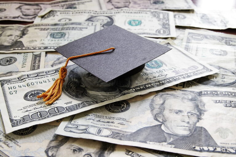 Image is of a graduation cap placed across scattered cash, concept of drug charges affecting college funding and federal student aid access.