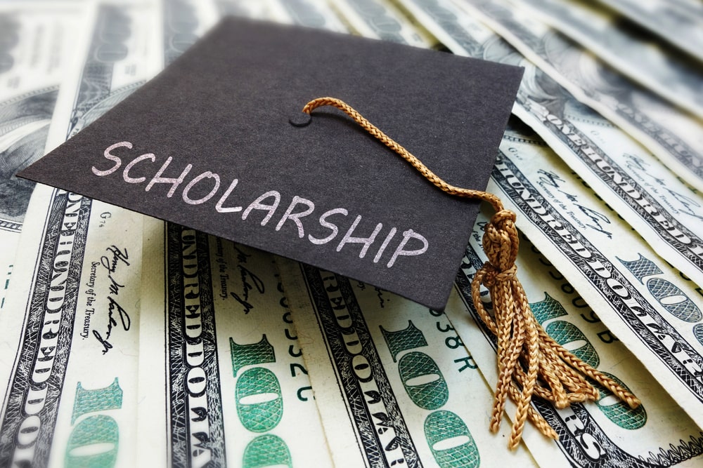 Image is of a graduation cap placed on top of money, concept of how drug charges may affect federal student aid and scholarship eligibility.