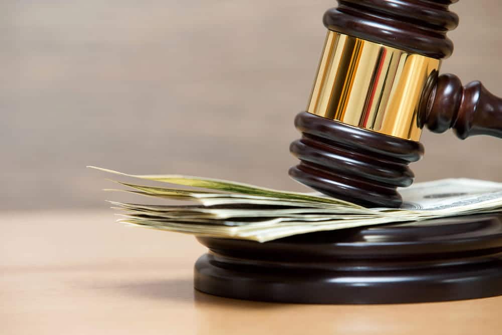Image is of a gavel near cash, concept of motorcycle accident settlement compensation after a serious injury claim.