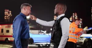 Image is of a police officer administering a breathalyzer test during a roadside stop, concept of DUI stops in Aiken