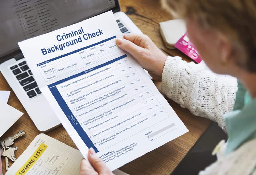 Image is of a person reviewing a printed criminal history document at a desk, concept of DUI-related background check reviews and record screening in Aiken.