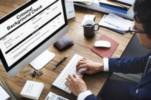 Image is of a professional reviewing digital criminal records on a desktop computer, concept of DUI background check screening and employment record searches in Aiken.