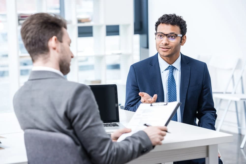 Image is of a professional discussing records and hiring concerns during an office meeting, concept of DUI-related background check evaluations and employment screenings in Aiken.