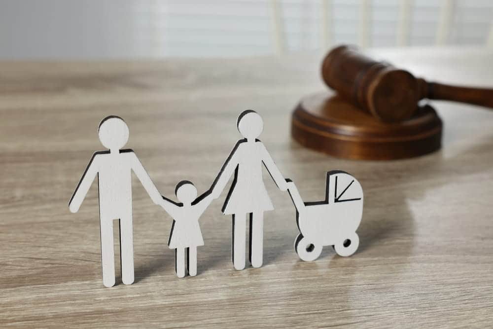 Image is of a family silhouette with children positioned near a courtroom gavel, concept of an Aiken adoption lawyer helping families complete the legal adoption process.