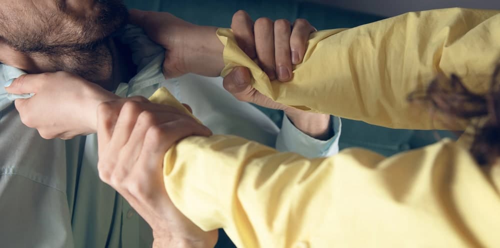 Image is of an individual grabbing another person during a physical confrontation, concept of an assault and battery lawyer defending clients accused of violent conduct.