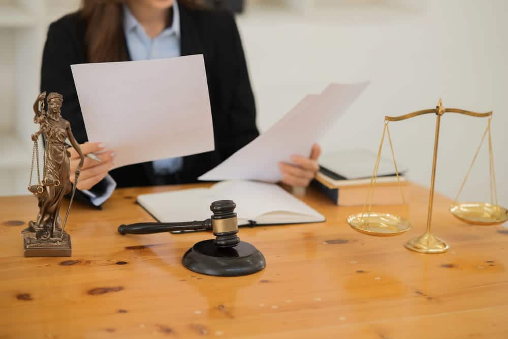 Image is of an attorney reviewing legal documents beside scales of justice and a gavel, concept of an Aiken burglary lawyer assessing evidence and defense strategies.