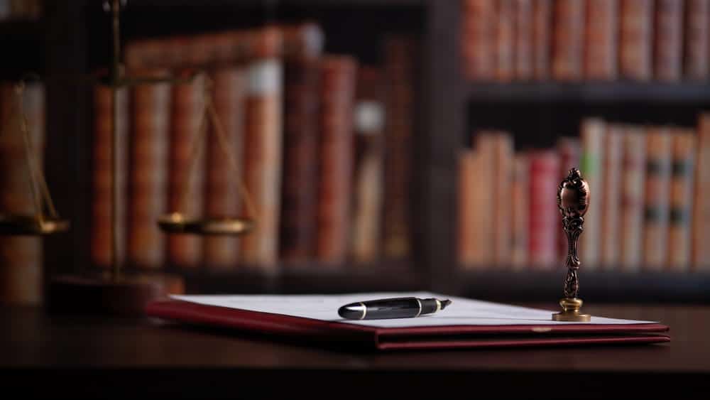 Image is of legal documents and a pen on a desk in a law office, concept of case preparation by a child support lawyer in Aiken.