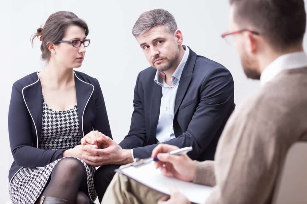 Image is of a couple meeting with a legal professional to discuss unresolved marital issues, concept of representation by a contested divorce lawyer in Aiken.
