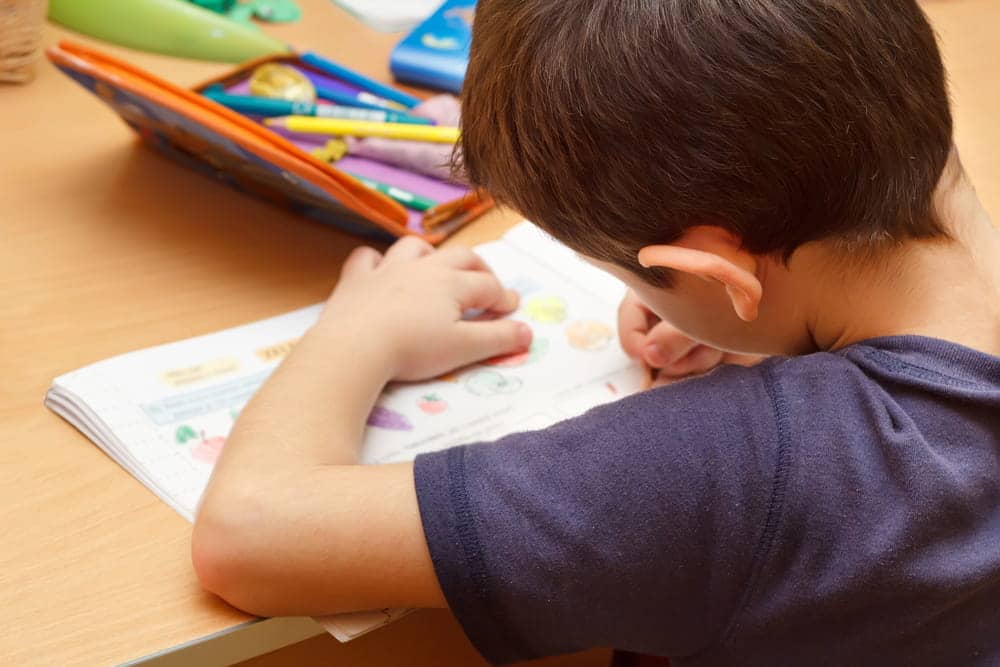Image is of a child working on school assignments at a desk, concept of an Aiken custody modification lawyer addressing changes related to a child's educational needs.