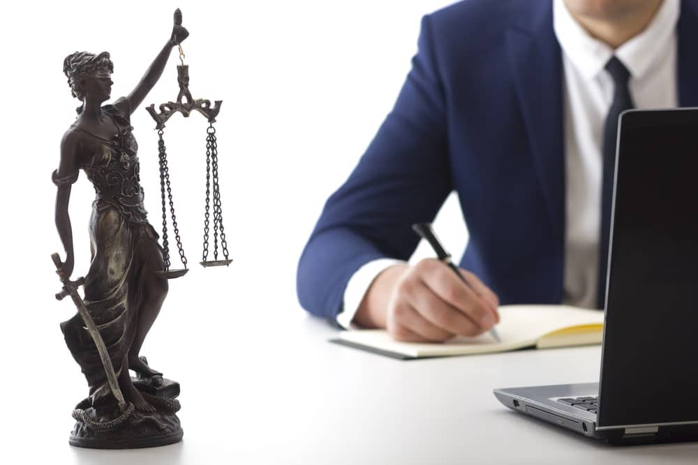 Image is of an attorney preparing legal documents with a gavel and Lady Justice statue nearby, concept of a DUI license suspension lawyer evaluating defense options.