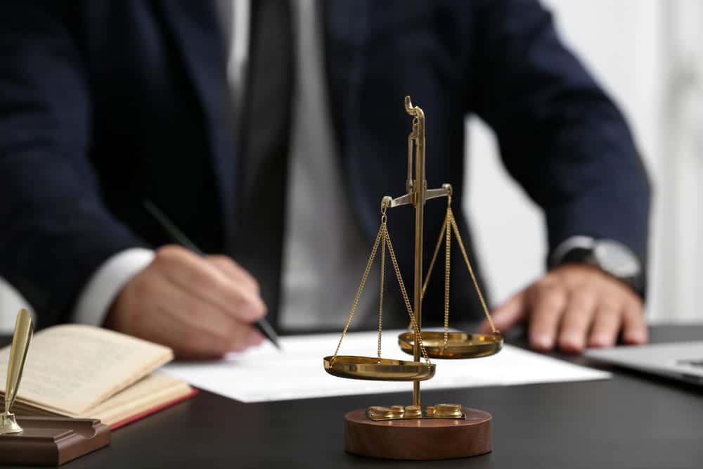 Image is of an attorney reviewing legal documents beside the scales of justice, concept of an Aiken defective drugs lawyer preparing a defective medication case.