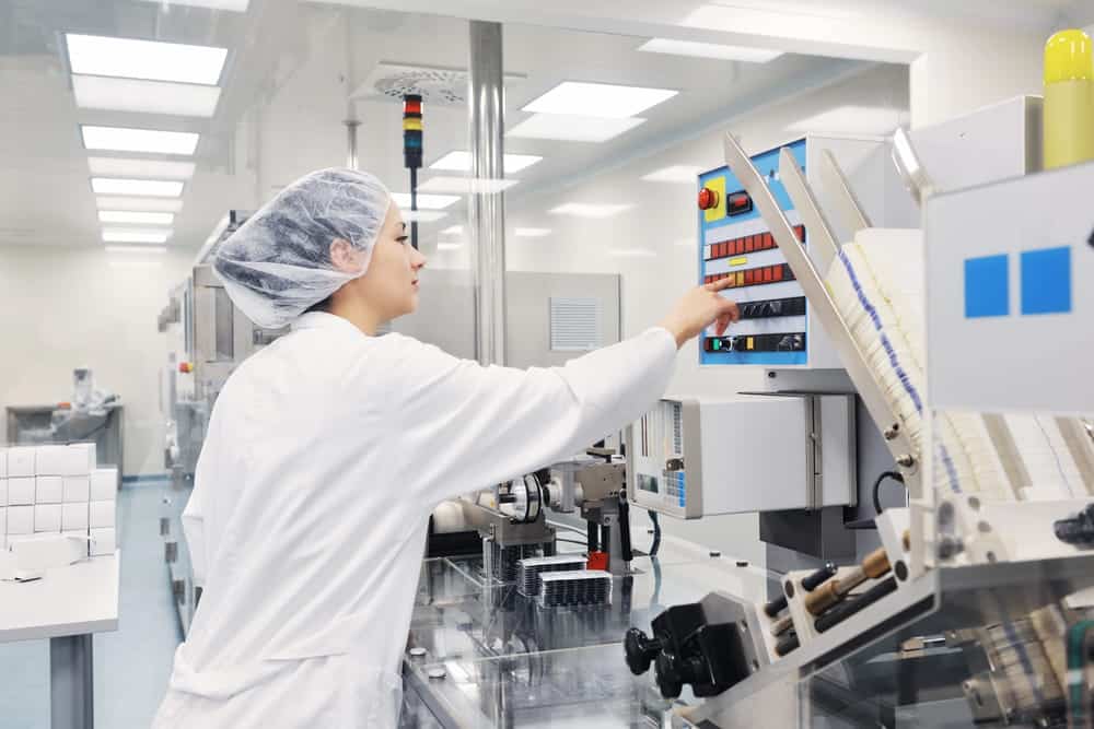 Image is of a pharmaceutical manufacturing technician operating production equipment, concept of an Aiken defective drugs lawyer investigating medication manufacturing defects.