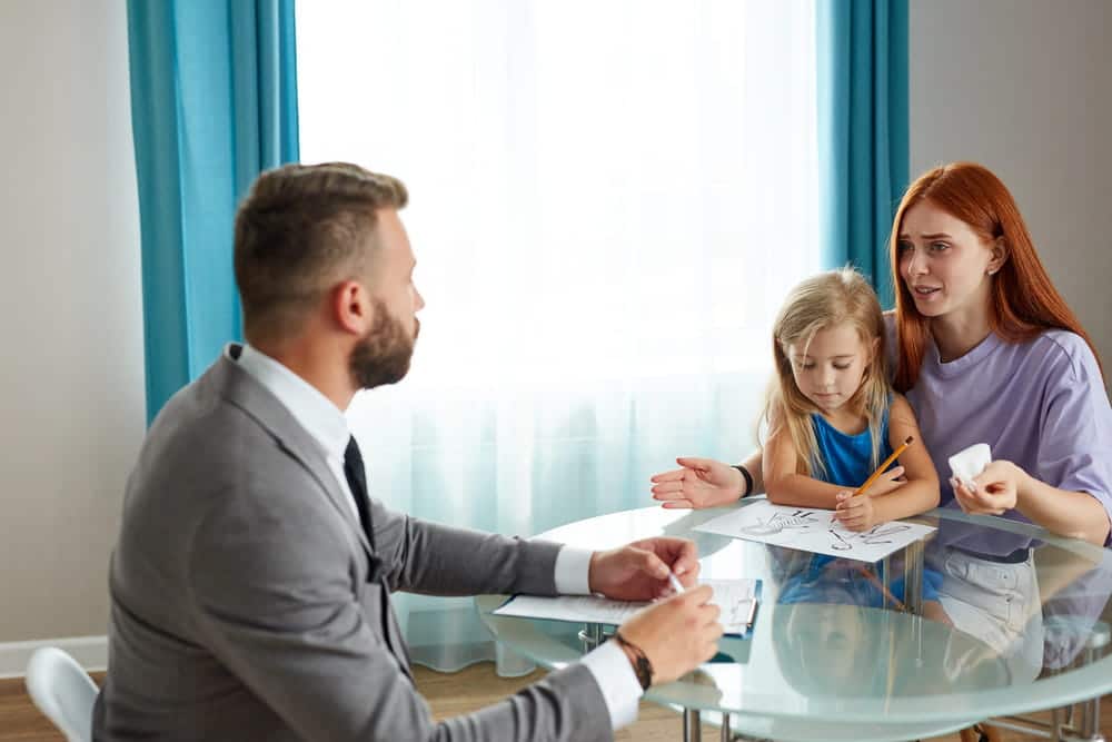 Image is of a parent meeting with an attorney while a child sits nearby, concept of a divorce with children lawyer discussing custody and parenting arrangements.