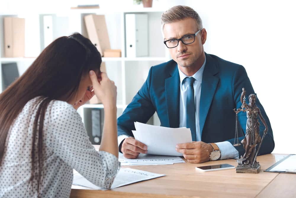 Image is of an attorney meeting with a client while reviewing legal documents, concept of a domestic violence lawyer explaining legal options and defense strategies.