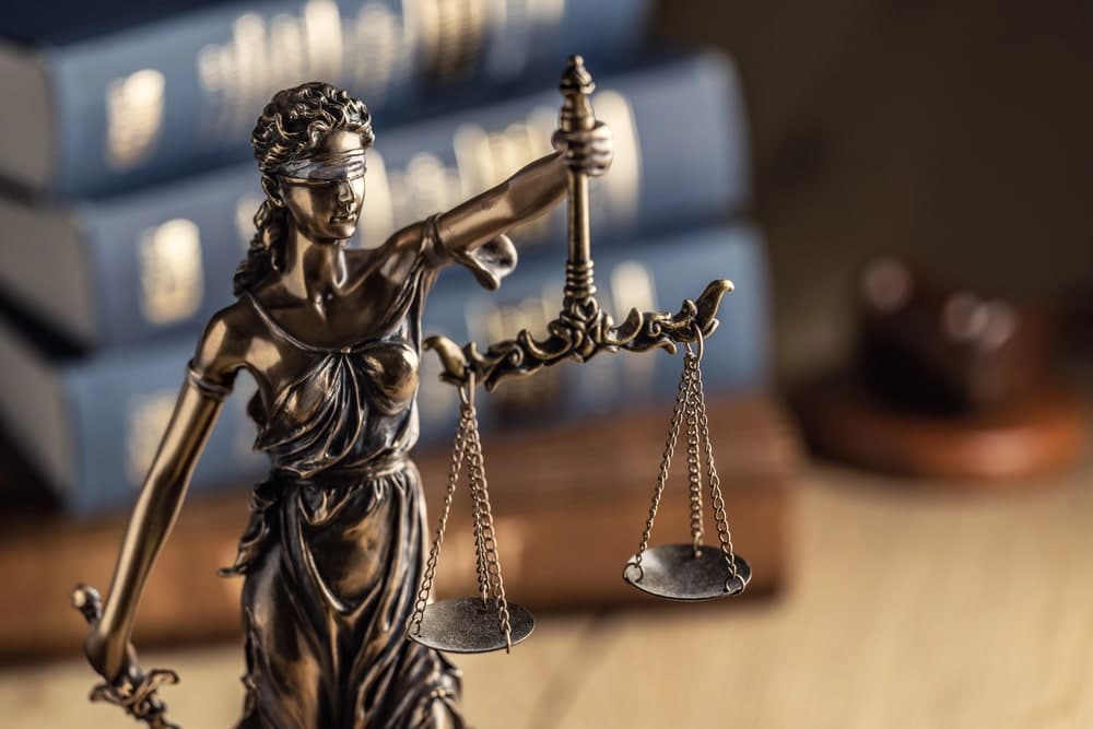Image is of a Lady Justice statue displayed in front of legal books, concept of an Aiken drug crimes lawyer providing criminal defense representation.