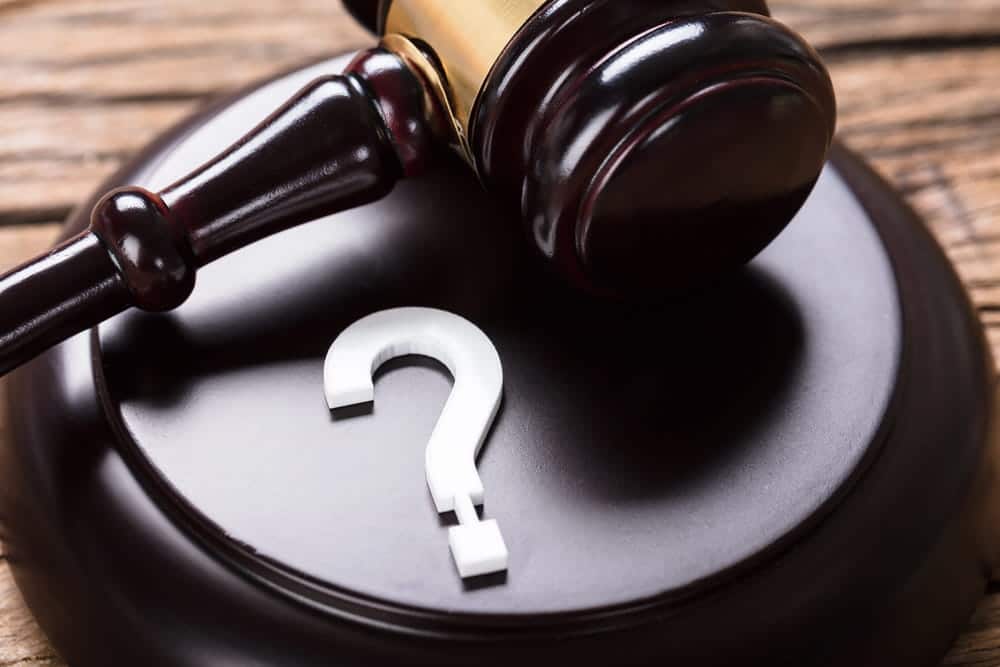 Image is of a judge's gavel resting beside a question mark, concept of an Aiken drug manufacturing lawyer providing legal guidance during a criminal investigation.