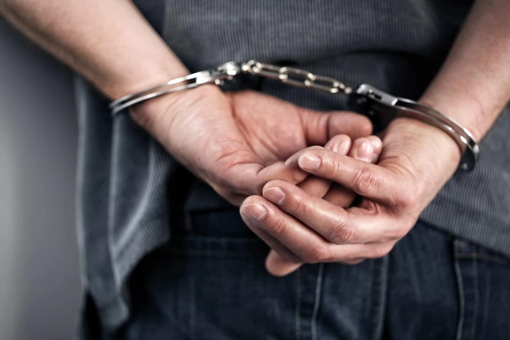 Image is of a person wearing handcuffs behind their back, concept of an Aiken drunk driving accident lawyer helping individuals understand the legal issues that may arise after an alcohol-related crash.