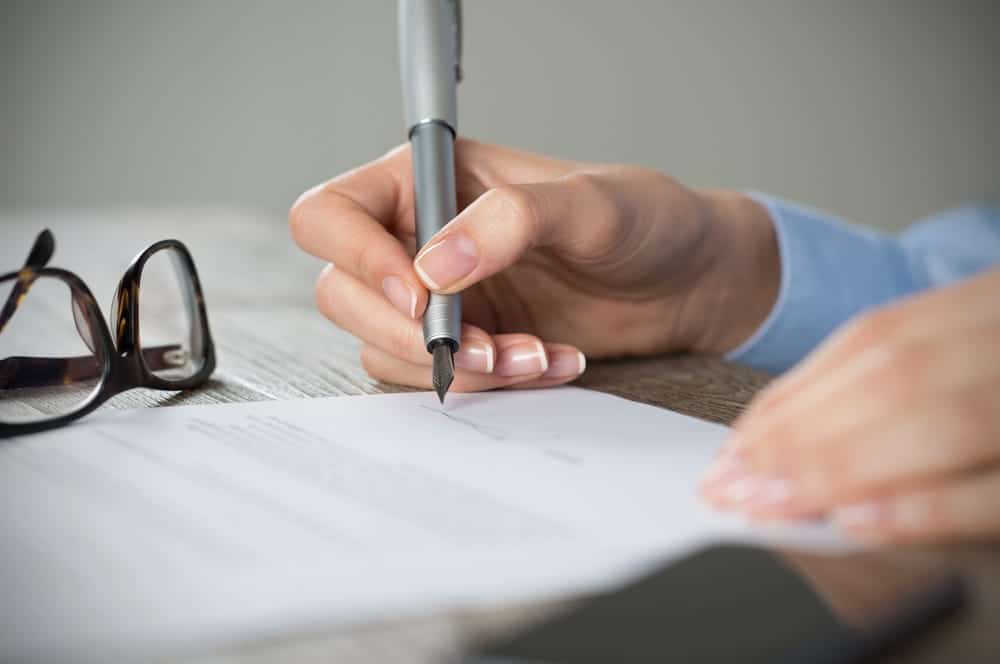 Image is of an individual signing legal documents, concept of an Aiken expungement lawyer assisting with expungement applications and related paperwork.