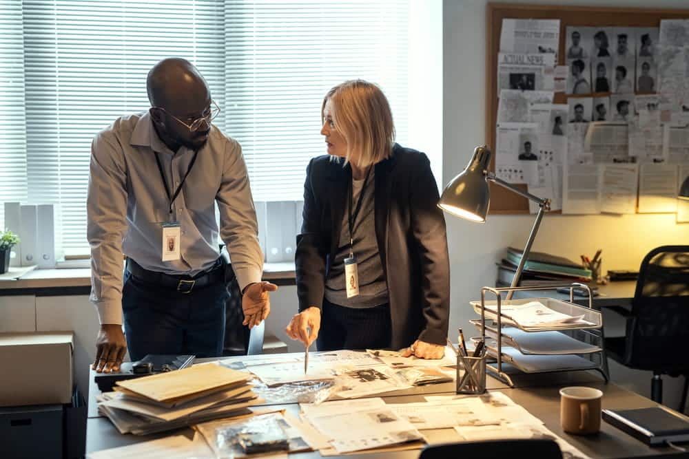 Image is of investigators reviewing evidence and case documents in an office, concept of a federal crimes lawyer analyzing facts and preparing for a federal criminal defense case.