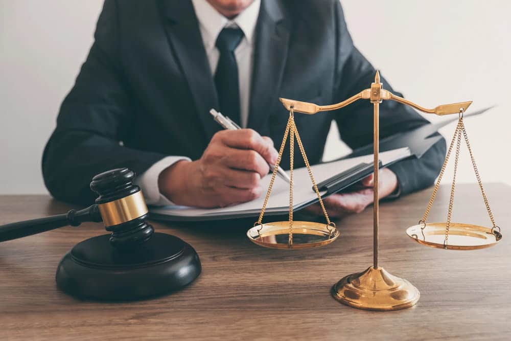 Image is of an attorney reviewing legal documents beside a gavel and scales of justice, concept of Aiken felony lawyer evaluating felony defense strategies.