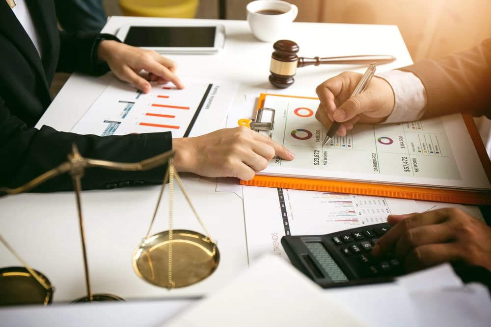 Image is of professionals reviewing financial reports and charts during a meeting, concept of an Aiken fraud lawyer analyzing business records in a criminal case.