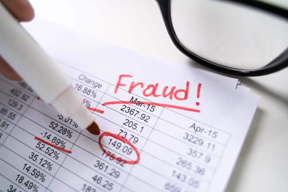 Image is of financial documents marked for suspected fraud, concept of an Aiken fraud lawyer reviewing evidence in a financial crime investigation.