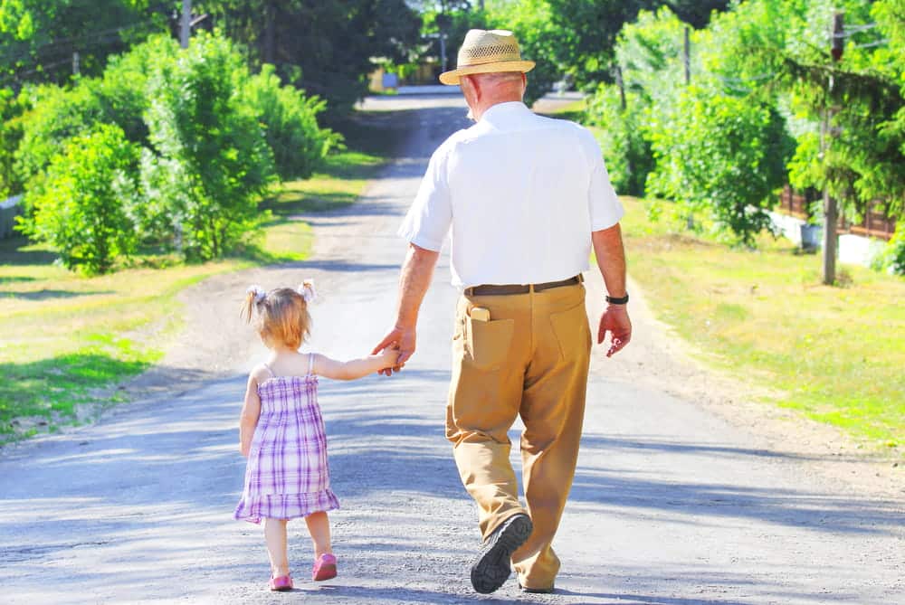 Image is of a grandparent walking hand in hand with a young child outdoors, concept of an Aiken grandparents' rights lawyer advocating for continued grandparent involvement in a child's life.