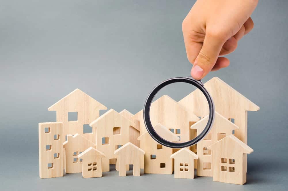 Image is of a magnifying glass examining multiple residential properties, concept of a high net worth divorce lawyer reviewing real estate assets during property division.