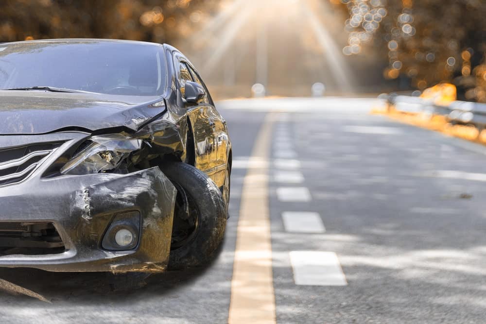 Image is of a damaged car stopped on the roadside after a collision, concept of a hit and run accident lawyer helping Aiken crash victims pursue compensation.