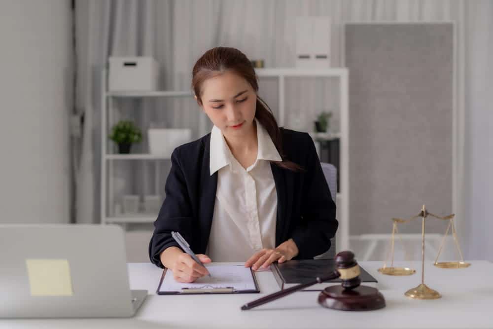 Image is of a lawyer reviewing legal documents at a desk with a judge's gavel and scales of justice, concept of an Aiken identity theft lawyer preparing a criminal defense case.