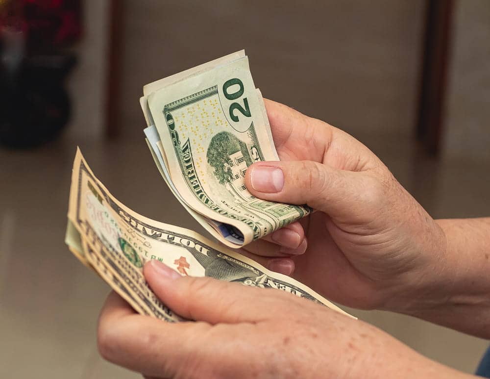 Image is of an individual counting money while reviewing financial resources and household expenses, concept of a legal separation lawyer.