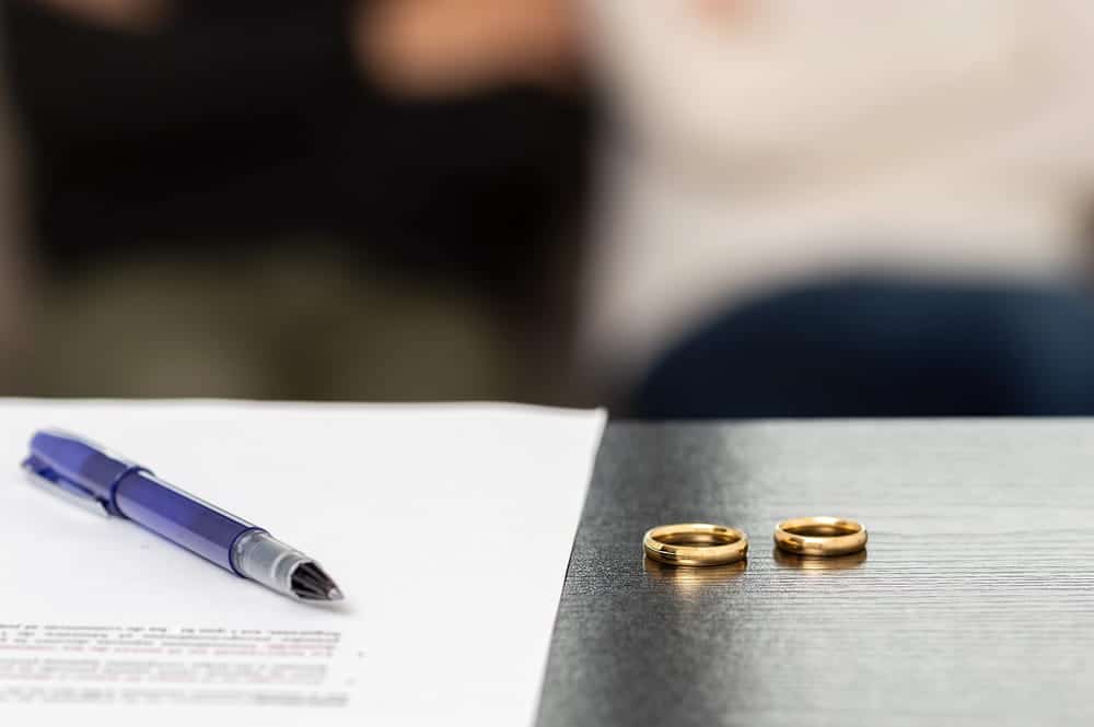 Image is of legal paperwork and wedding rings representing marital separation and related legal decisions, concept of a legal separation lawyer.