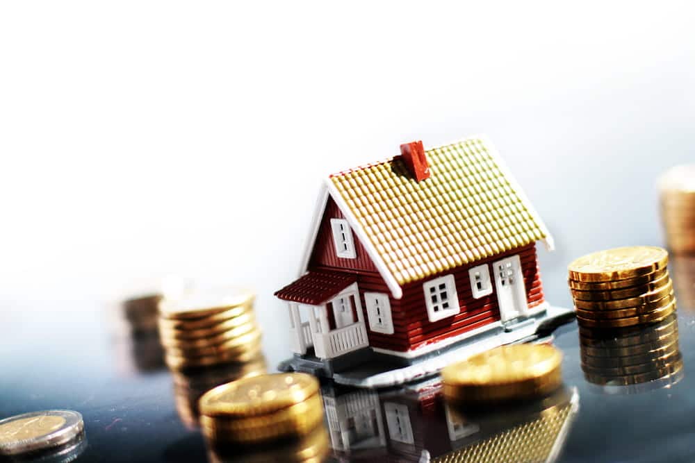 Image is of a model home surrounded by coins representing the valuation of marital property and financial assets, concept of a marital property division lawyer.