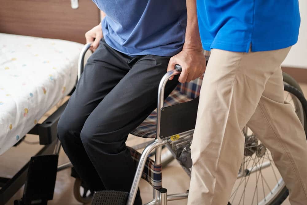 Image is of a caregiver assisting a patient into a wheelchair, concept of an Aiken medical malpractice lawyer helping individuals affected by serious medical negligence.