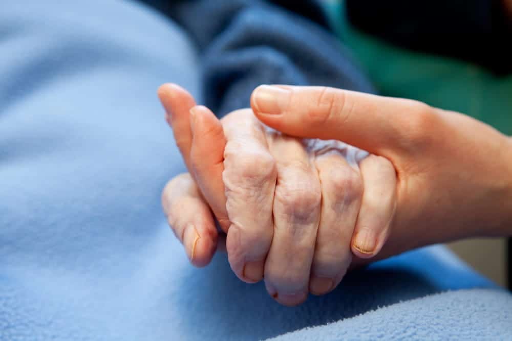 Image is of a caregiver holding a patient's hand during recovery, concept of an Aiken medical malpractice lawyer supporting victims harmed by medical errors.