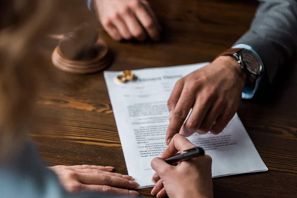 Image is of individuals reviewing and signing divorce paperwork, concept of legal guidance provided by a military divorce lawyer in Aiken.