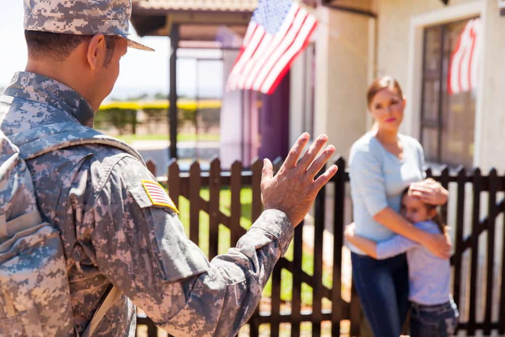 Image is of a military service member speaking with a parent and child outside a home, concept of family transition issues addressed by a military divorce lawyer in Aiken.