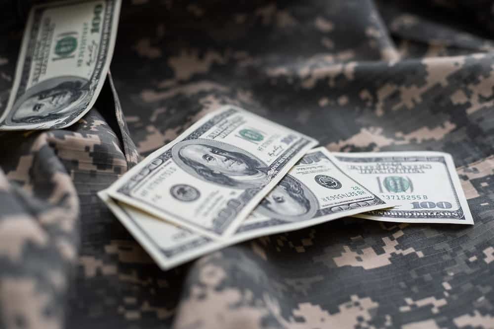 Image is of military uniform fabric with cash placed on top, concept of financial issues reviewed by a military divorce lawyer in Aiken.