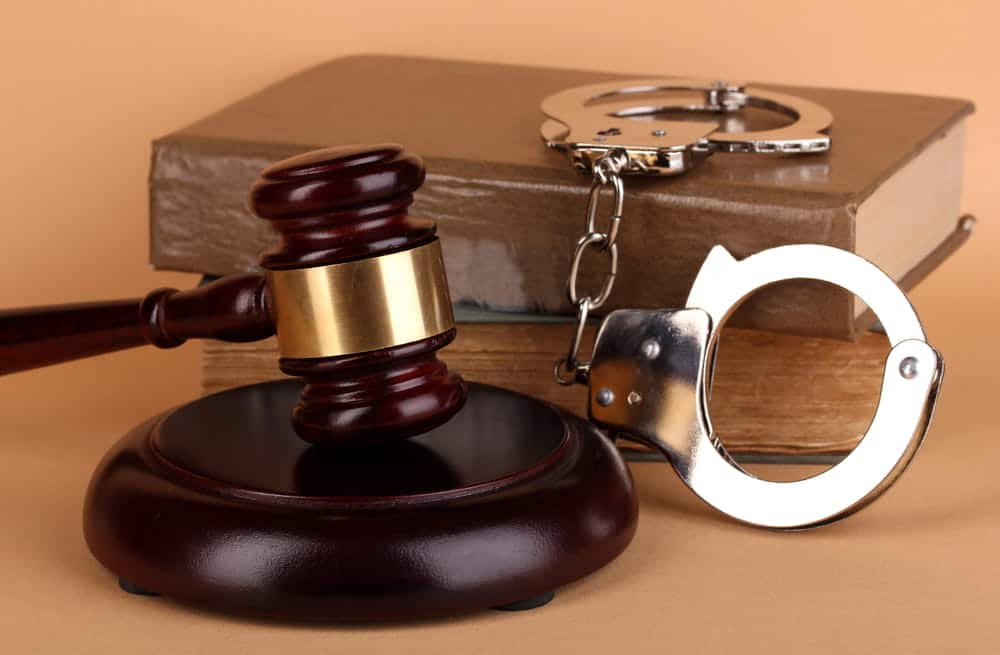 Image is of a gavel, handcuffs, and a law book used in criminal proceedings, concept of Aiken misdemeanor lawyer representing individuals facing criminal allegations.
