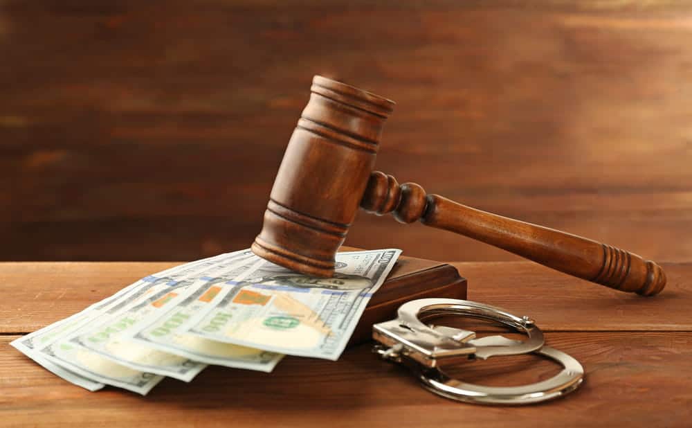 Image is of a judge's gavel resting on U.S. currency beside handcuffs, concept of an Aiken money laundering lawyer defending financial crime allegations.