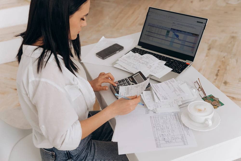 Image is of a person reviewing receipts and financial records beside a laptop, concept of an Aiken money laundering lawyer analyzing financial transaction evidence.