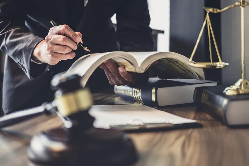 Image is of an attorney reviewing legal books and documents, concept of a motorcycle accident lawyer preparing evidence and legal arguments.