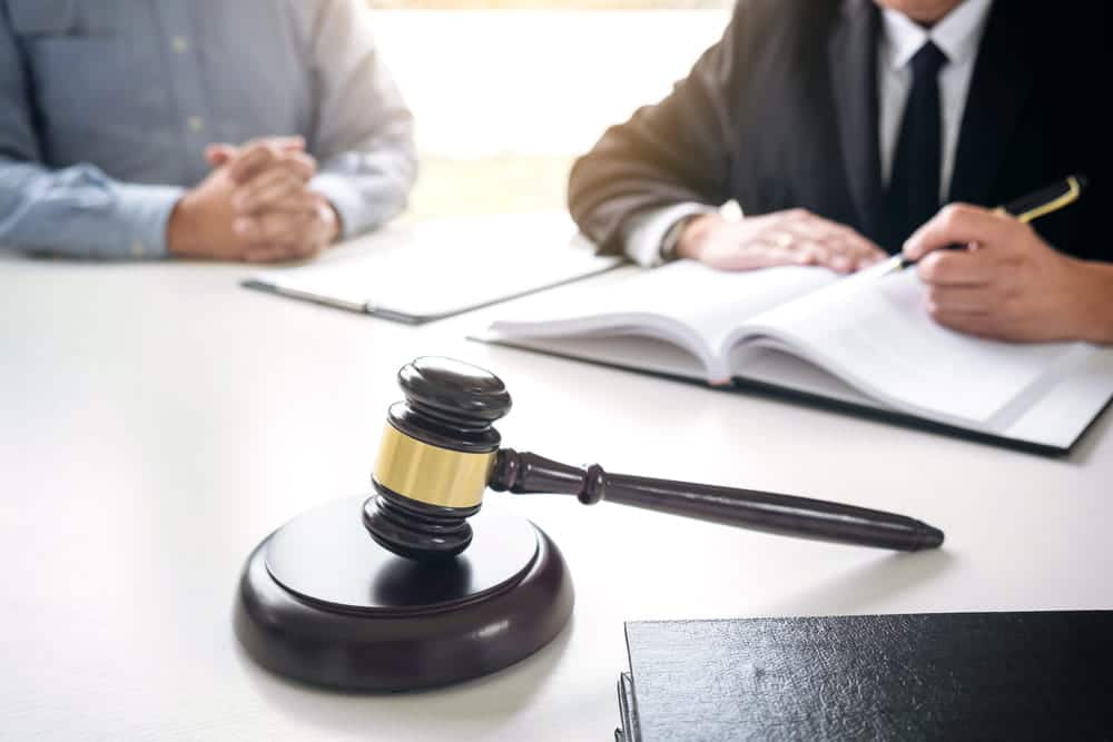 Image is of a lawyer meeting with a client at a consultation desk, concept of an Aiken murder defense lawyer discussing legal options and case strategy.