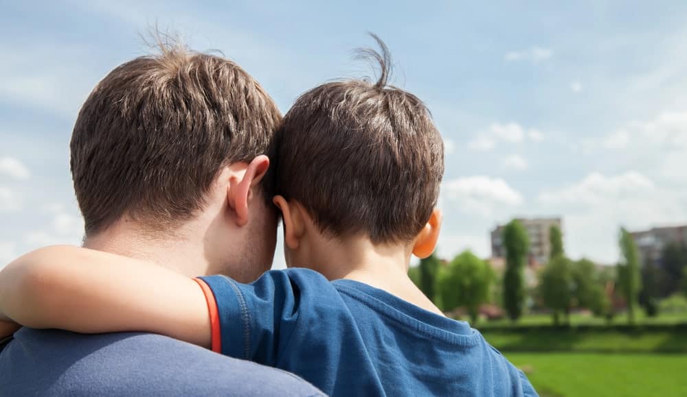 Image is of a parent and child embracing while looking across an open field, concept of an Aiken paternity lawyer protecting parent child relationships through legal action.