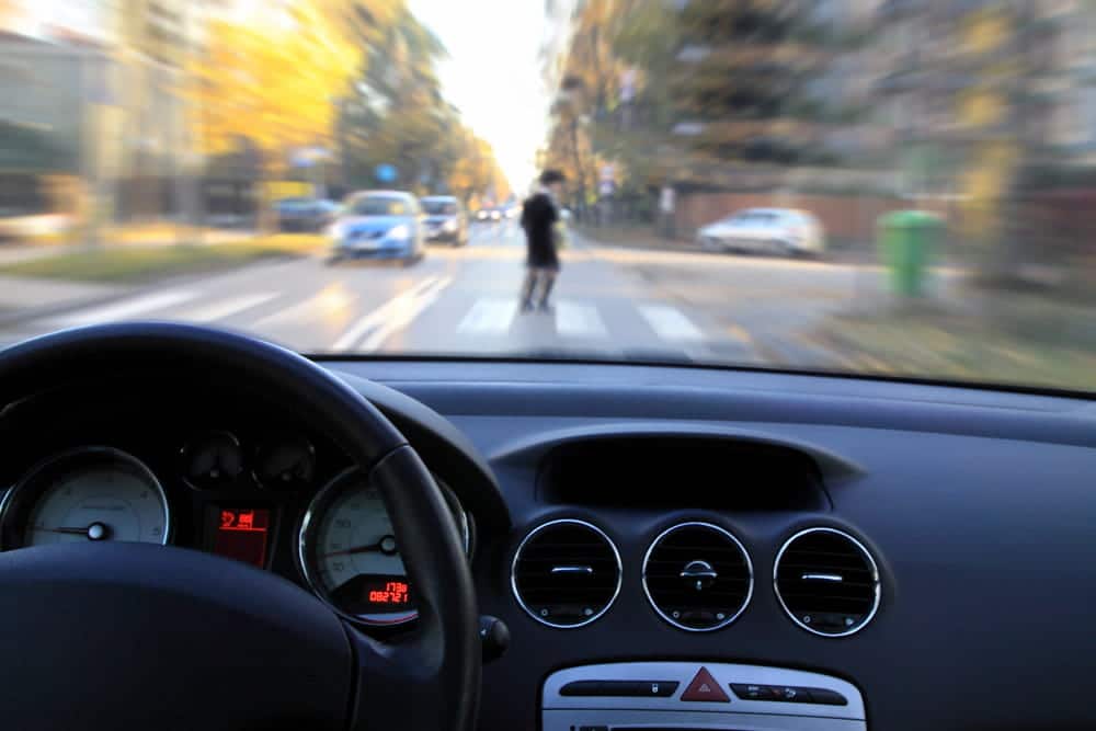 Image is of a driver approaching a pedestrian crossing, concept of a pedestrian accident lawyer investigating driver awareness and roadway safety.
