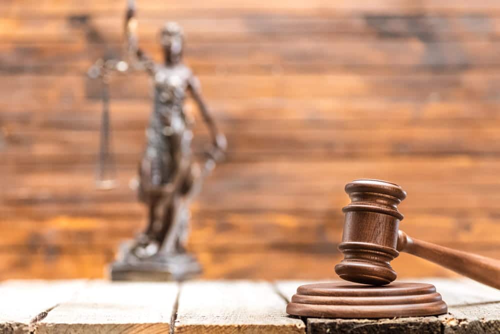 Image is of a gavel and Lady Justice statue on a table, concept of a pedestrian accident lawyer handling injury claims and legal disputes.